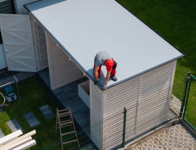 Worker Installing Roof on Wooden Shed